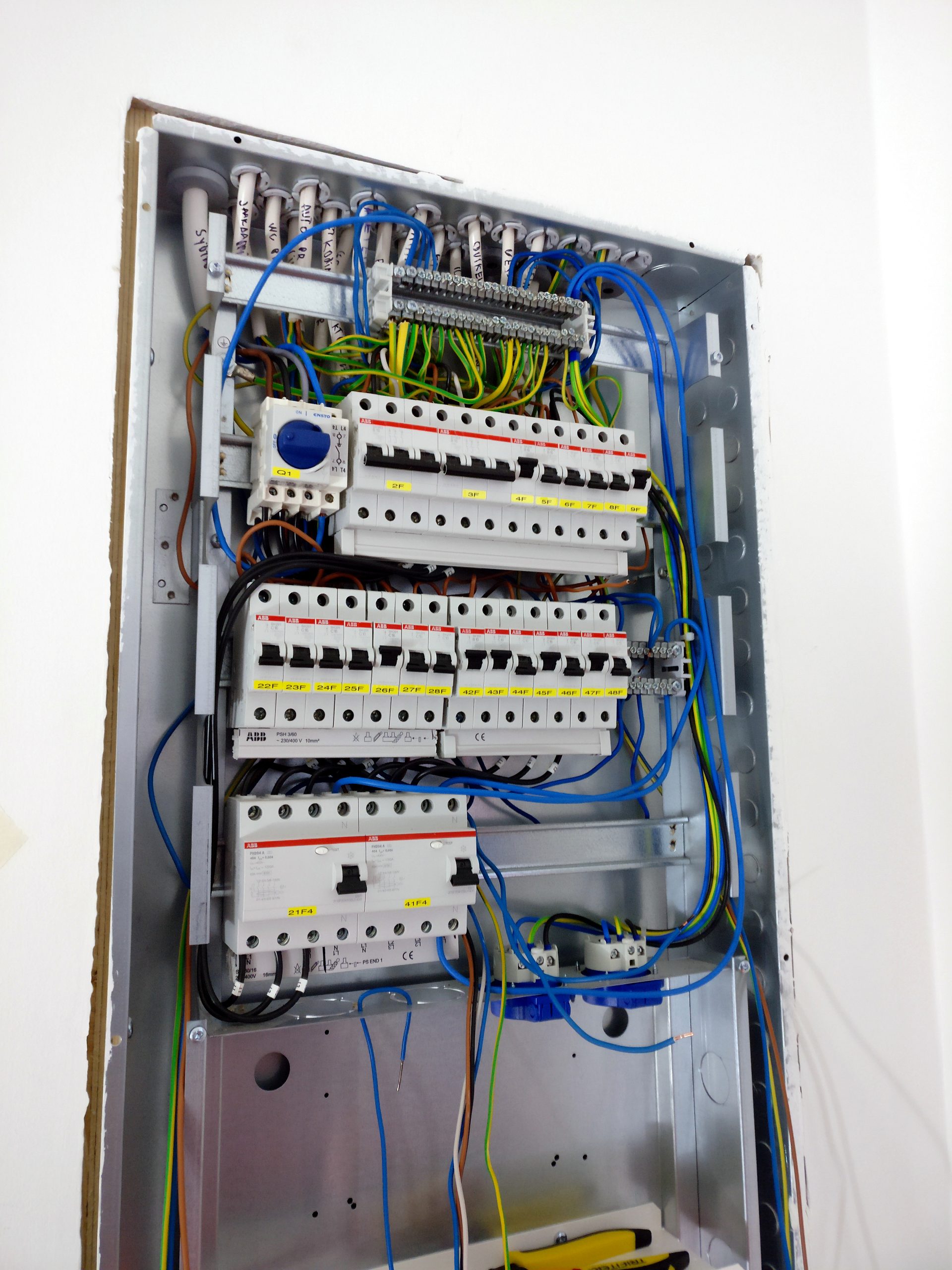 Open electrical distribution board showing circuit breakers and internal wiring